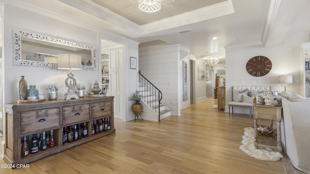 interior space featuring visible vents, crown molding, a chandelier, stairway, and light wood-style flooring