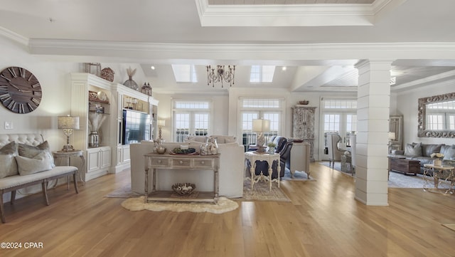 living area with a raised ceiling, decorative columns, light wood-style floors, and ornamental molding