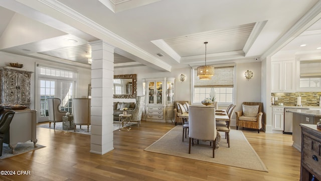 dining space featuring visible vents, light wood finished floors, a tray ceiling, decorative columns, and ornamental molding