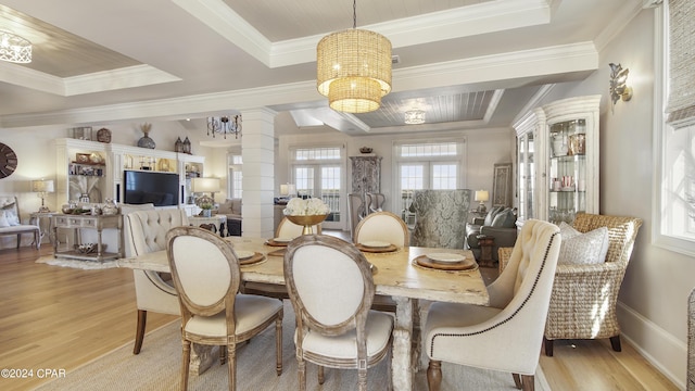 dining space with decorative columns, a raised ceiling, light wood-style floors, and crown molding