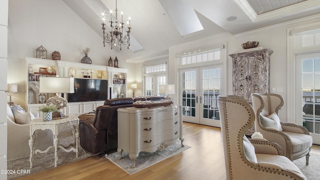 living area featuring an inviting chandelier, french doors, light wood-style floors, and ornamental molding