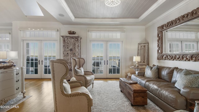 living area featuring french doors, wood finished floors, a raised ceiling, and ornamental molding