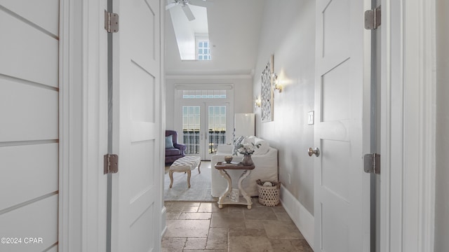 bathroom with baseboards, a high ceiling, stone tile flooring, and a ceiling fan