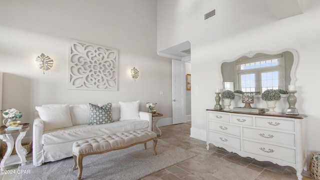 living area with visible vents, baseboards, and a towering ceiling