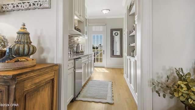 bar featuring a sink, light wood-style floors, dishwasher, and crown molding