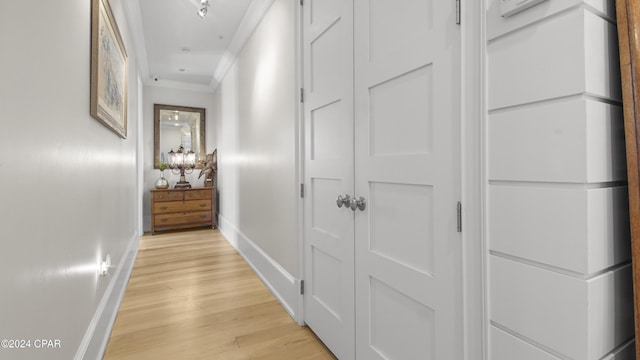 corridor featuring light wood-style flooring, baseboards, and ornamental molding