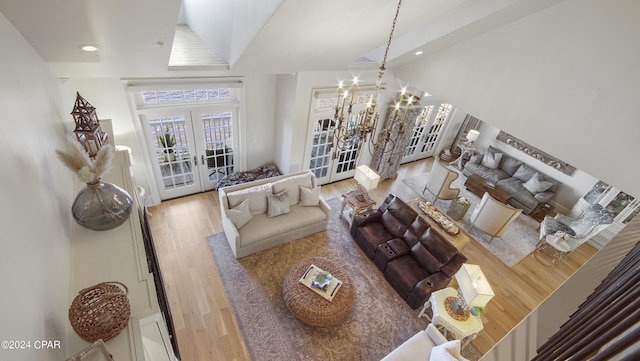 living area featuring a notable chandelier, wood finished floors, recessed lighting, french doors, and lofted ceiling