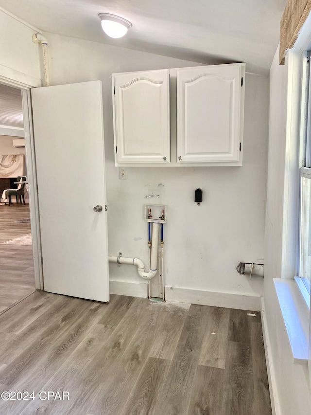 clothes washing area with washer hookup, light wood-type flooring, and cabinets