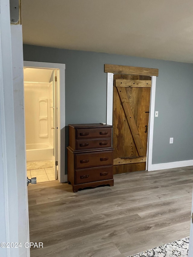 unfurnished bedroom featuring connected bathroom and light wood-type flooring