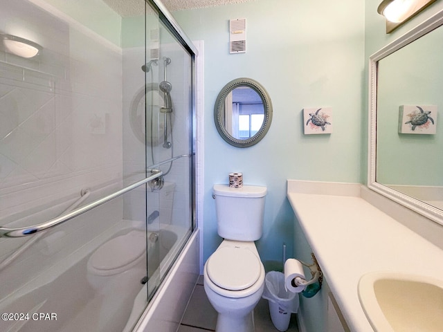 full bathroom featuring a textured ceiling, shower / bath combination with glass door, toilet, vanity, and tile patterned floors