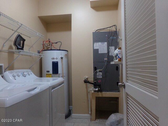 laundry room with water heater, washer and dryer, and light tile patterned flooring