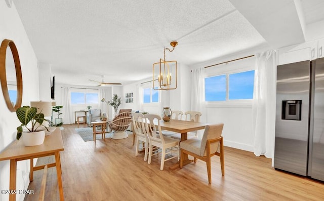 dining area featuring ceiling fan with notable chandelier, a textured ceiling, and light wood-type flooring