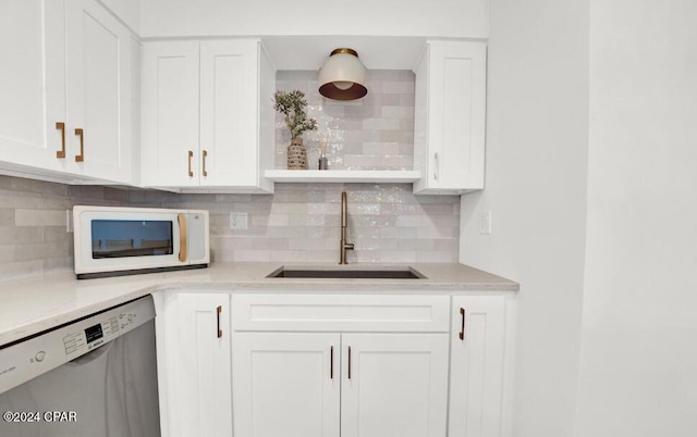 5801 Thomas Dr Unit 501, Panama City, FL 32408 - kitchen featuring dishwasher, a sink, white microwave, white cabinets, and decorative backsplash
