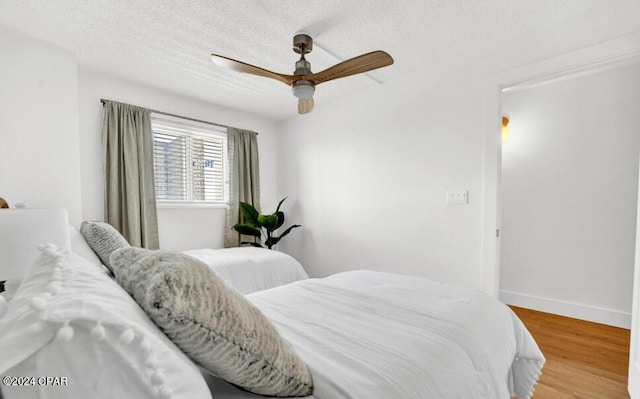 bedroom with ceiling fan, a textured ceiling, and hardwood / wood-style floors