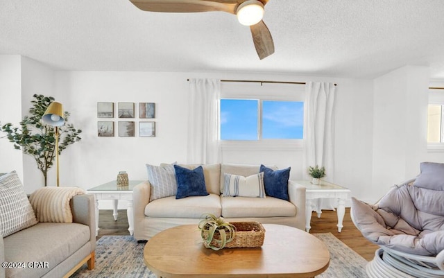 living room with a textured ceiling, wood-type flooring, and ceiling fan