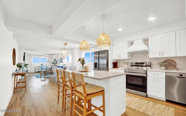 5801 Thomas Dr Unit 501, Panama City, FL 32408 - kitchen with stainless steel appliances, custom range hood, light countertops, a breakfast bar, and recessed lighting