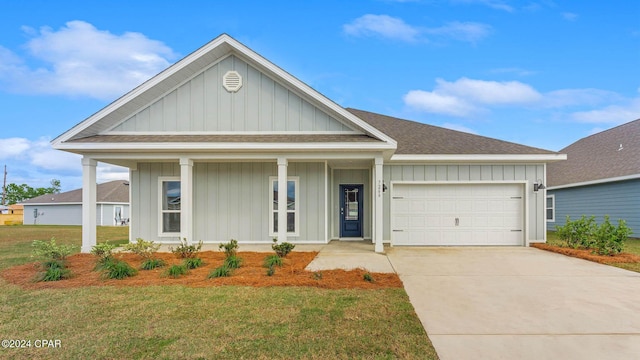 view of front of home featuring covered porch, a front yard, and a garage