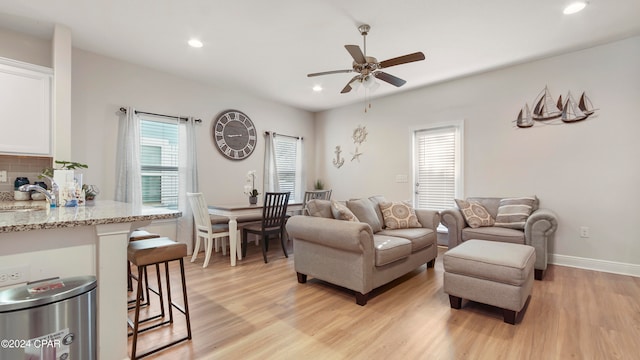 living room with ceiling fan, sink, and light wood-type flooring