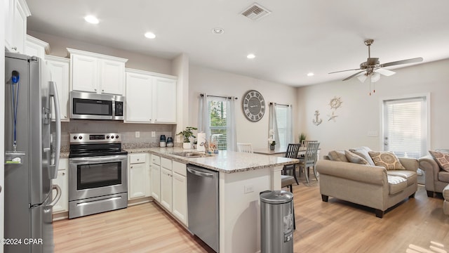 kitchen with white cabinetry, stainless steel appliances, and light wood-type flooring