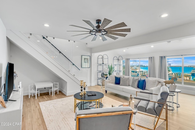 living room with a water view, light wood-type flooring, and ceiling fan