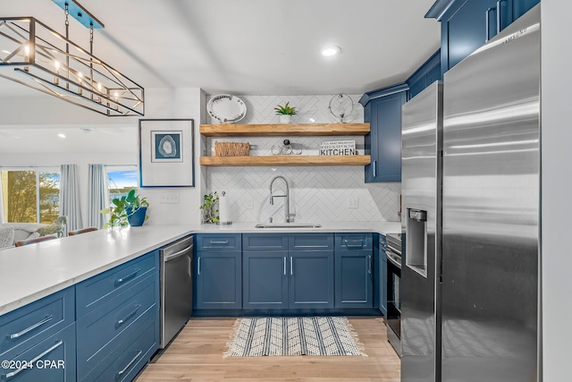 kitchen with sink, appliances with stainless steel finishes, light hardwood / wood-style flooring, and blue cabinets