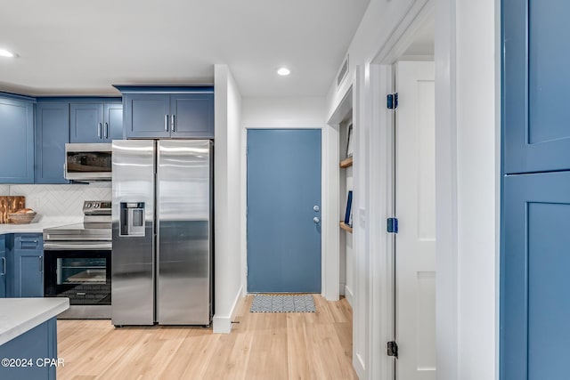 kitchen with light hardwood / wood-style floors, stainless steel appliances, backsplash, and blue cabinets