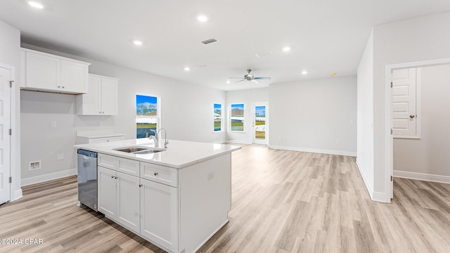 kitchen featuring white cabinets, a center island with sink, stainless steel dishwasher, and light hardwood / wood-style flooring