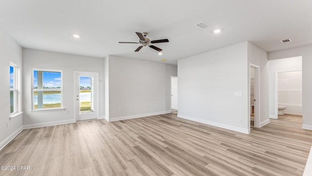 empty room featuring ceiling fan, light hardwood / wood-style flooring, and a water view