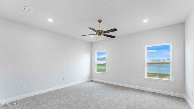 carpeted spare room with ceiling fan and a water view