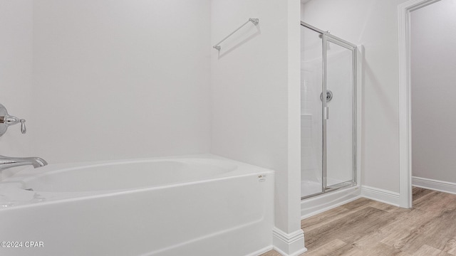 bathroom with hardwood / wood-style flooring and independent shower and bath