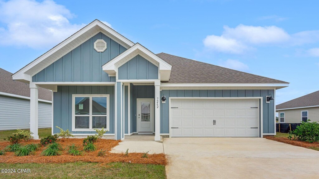 ranch-style house featuring a shingled roof, board and batten siding, an attached garage, and concrete driveway