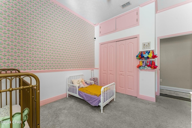 bedroom featuring a closet, light carpet, ornamental molding, and a crib