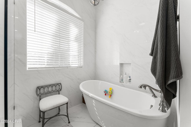 bathroom with a tub to relax in and tile walls