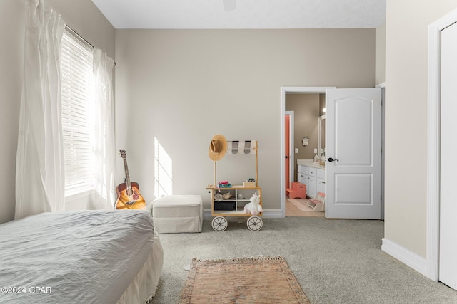 bedroom featuring light carpet, ensuite bathroom, and ceiling fan