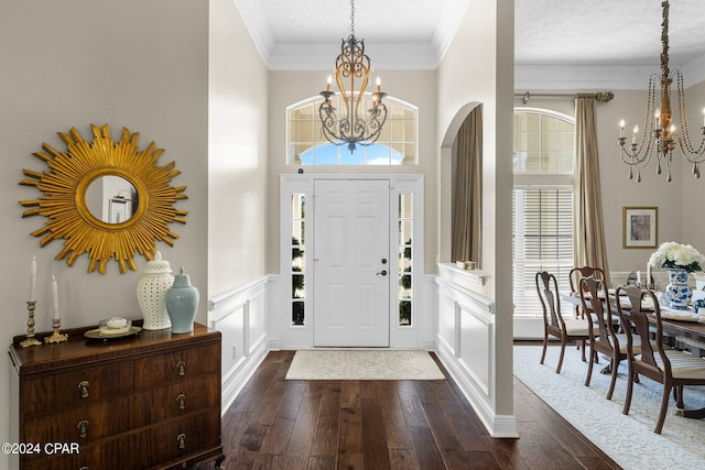 foyer entrance with dark wood-type flooring, a notable chandelier, ornamental molding, and a textured ceiling