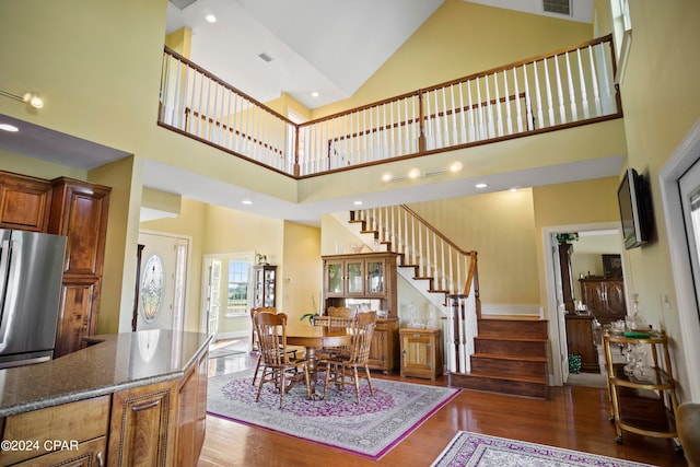 dining room with high vaulted ceiling and dark wood-type flooring