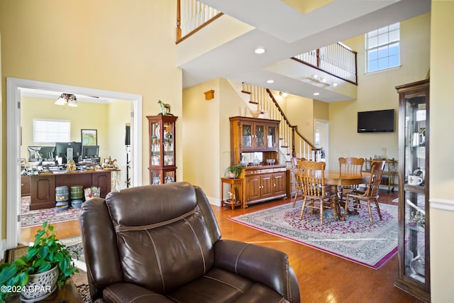 living room with a towering ceiling, a healthy amount of sunlight, and hardwood / wood-style flooring