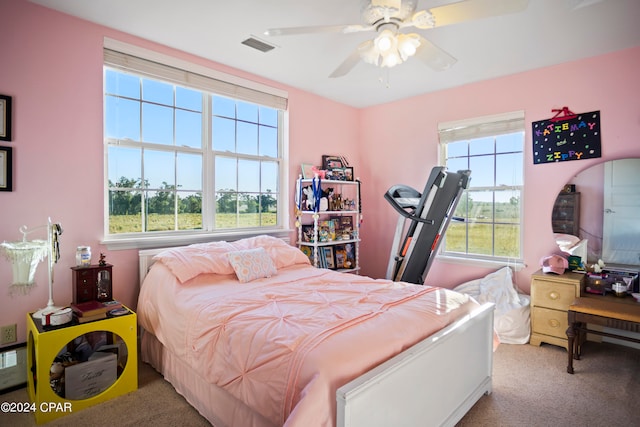 carpeted bedroom with multiple windows and ceiling fan