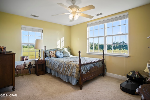 bedroom with ceiling fan, light colored carpet, and multiple windows