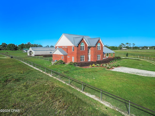 view of side of property with a rural view and a yard