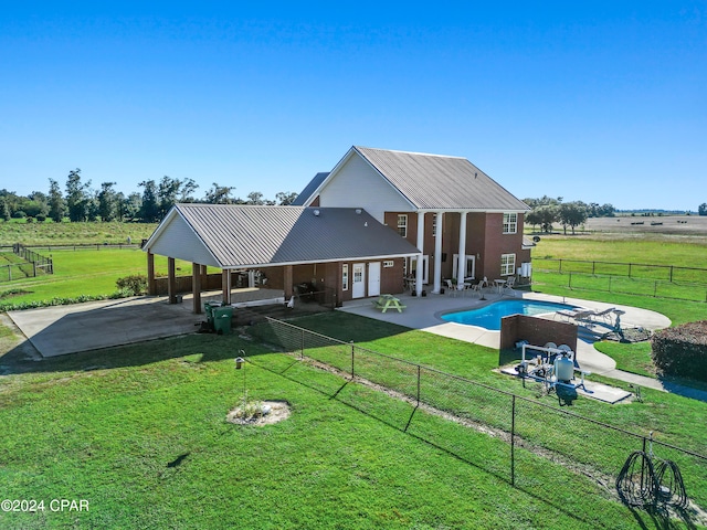 rear view of house featuring a yard, a rural view, and a patio area