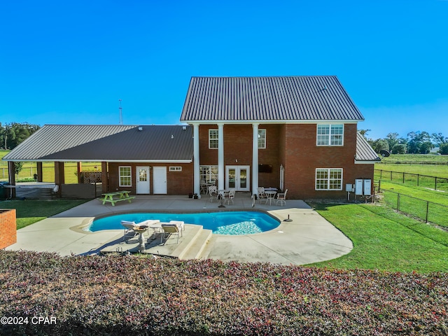 back of property with a lawn, a patio area, and french doors