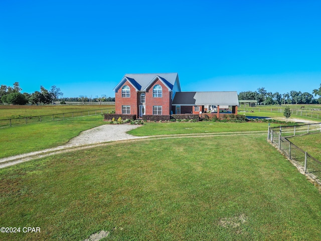 view of front of house with a rural view and a front lawn