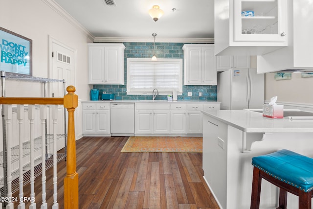 kitchen with white cabinets, hanging light fixtures, a kitchen breakfast bar, dark hardwood / wood-style floors, and white appliances