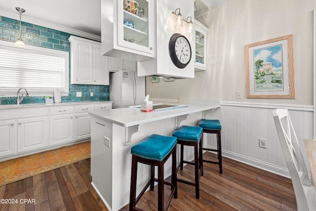 kitchen featuring kitchen peninsula, a breakfast bar, white cabinetry, dark hardwood / wood-style floors, and sink