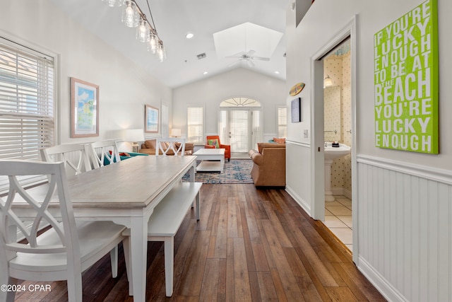 dining area with vaulted ceiling with skylight, ceiling fan, and dark hardwood / wood-style flooring