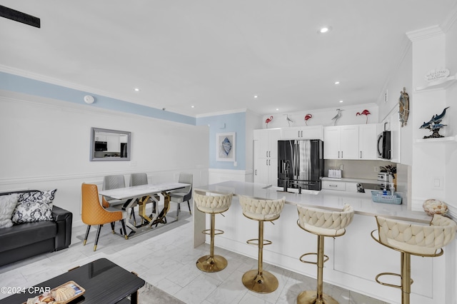 kitchen featuring stove, white cabinetry, a kitchen bar, black fridge with ice dispenser, and kitchen peninsula