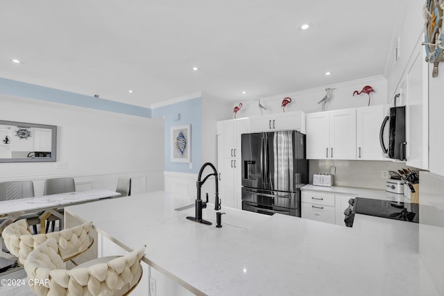 kitchen with sink, crown molding, a breakfast bar area, white cabinetry, and stainless steel refrigerator with ice dispenser