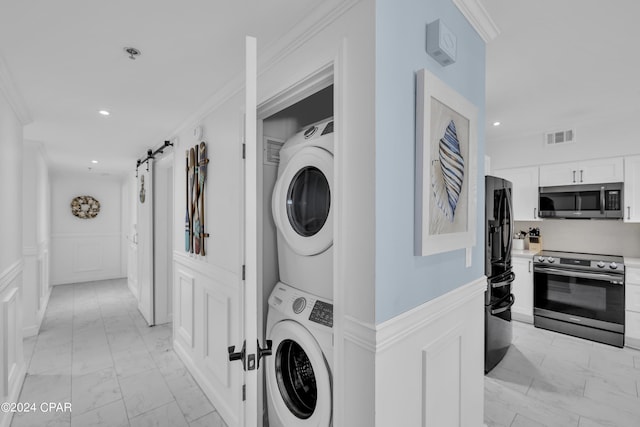 washroom featuring crown molding, a barn door, and stacked washer / drying machine