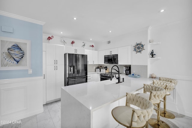 kitchen with white cabinetry, ornamental molding, black appliances, a kitchen bar, and kitchen peninsula